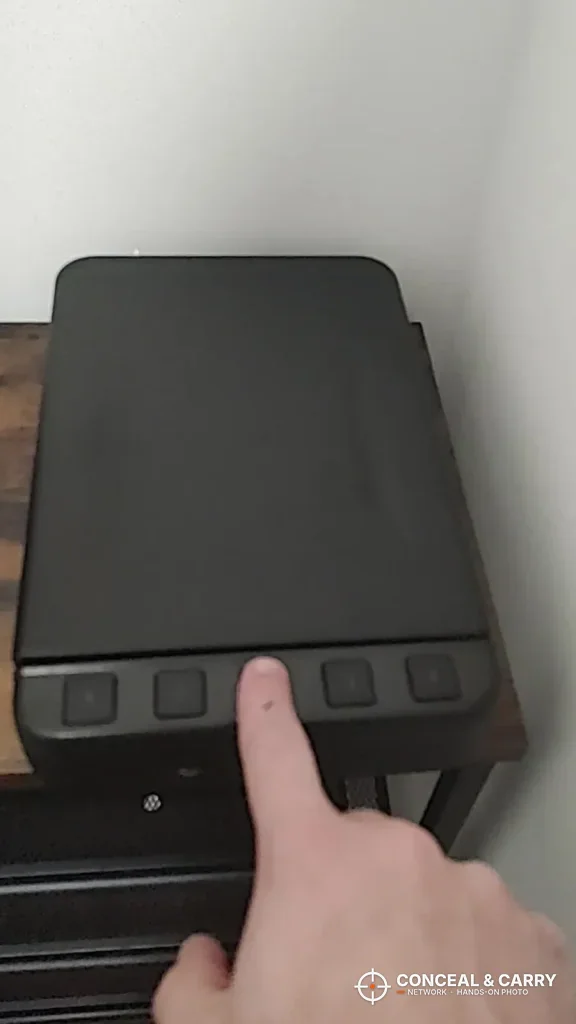 Finger on the fingerprint pad of the Langger lock box sitting on a nightstand