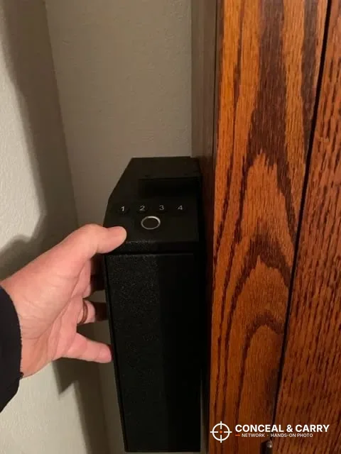 Hand reaching for the Langger slider safe mounted beside a wooden cabinet