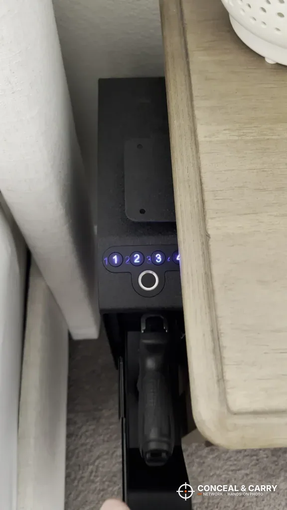 Langger slider safe between a bed and nightstand with the drawer open on a pistol grip