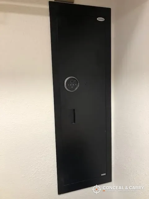 Black Langger in-wall biometric long gun safe set into a wall with the door closed