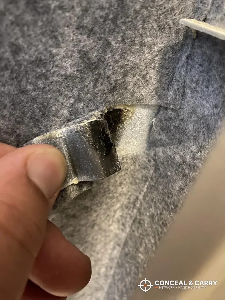 Thumb pulling back the gray felt lining inside the Langger in-wall safe
