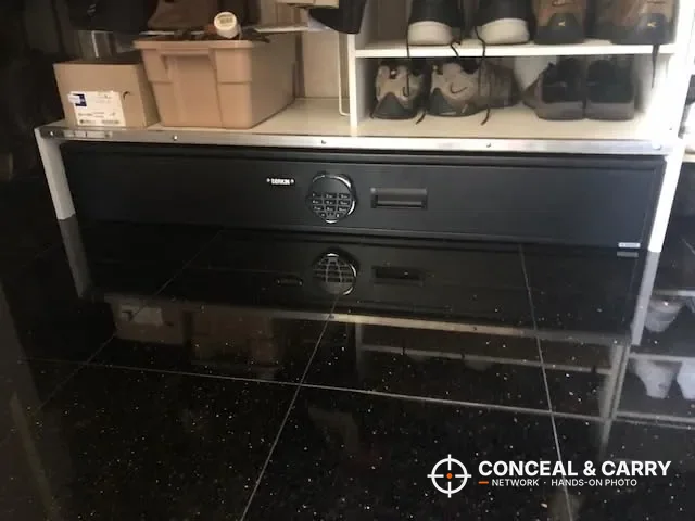 Langger under-bed gun safe closed on a tile floor under a closet shoe shelf