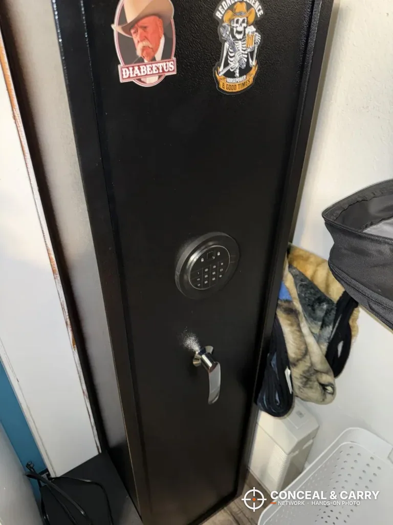 Marcree 8-10 gun safe standing in a corner beside hanging bags