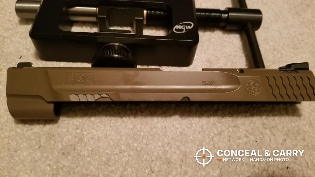 Bare pistol slide laid out in front of the MGW Glock sight tool