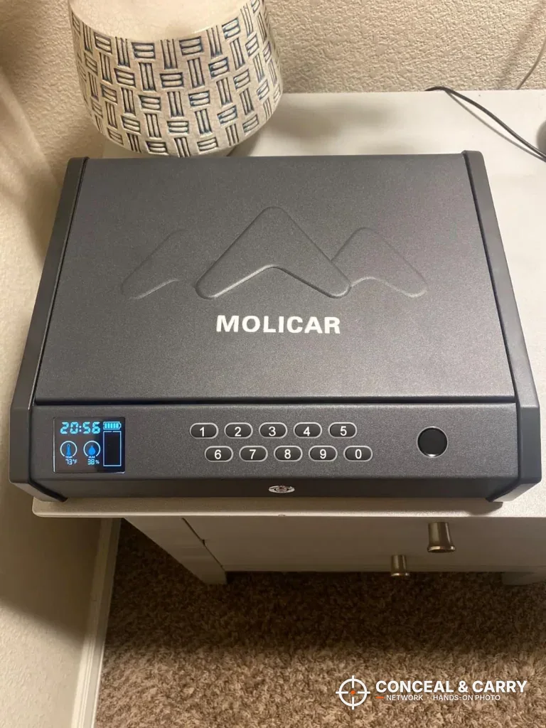 MOLICAR biometric bedside safe closed on a white nightstand with the screen lit
