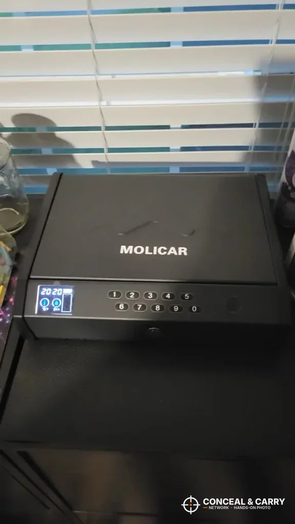 MOLICAR bedside safe on top of a black cabinet with the screen lit