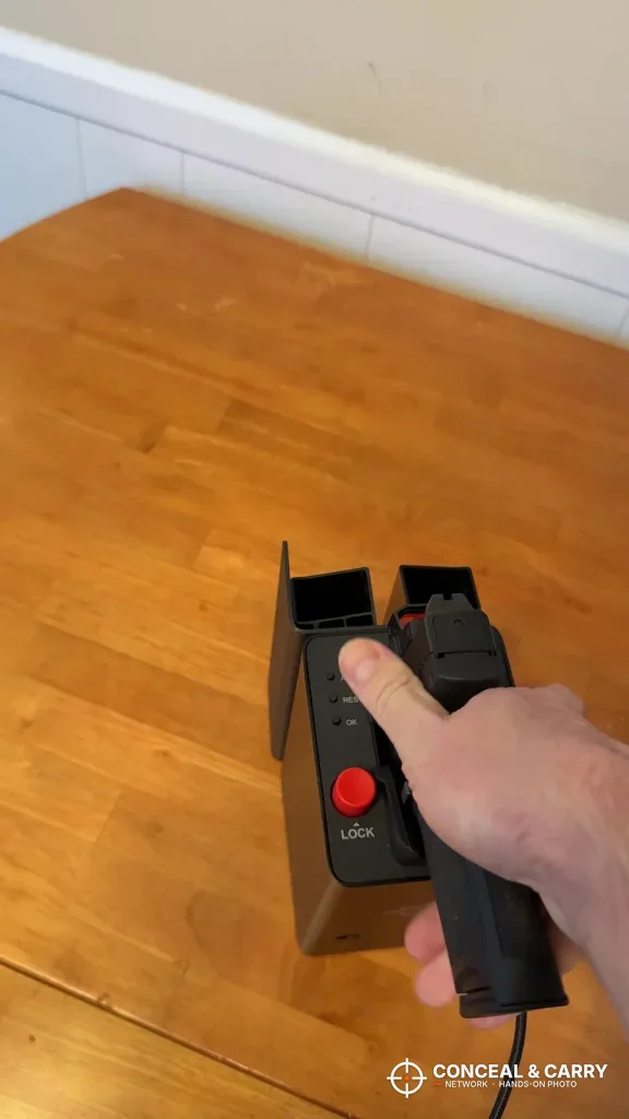 Hand gripping a pistol seated in the ONNAIS open-design safe on a wood floor