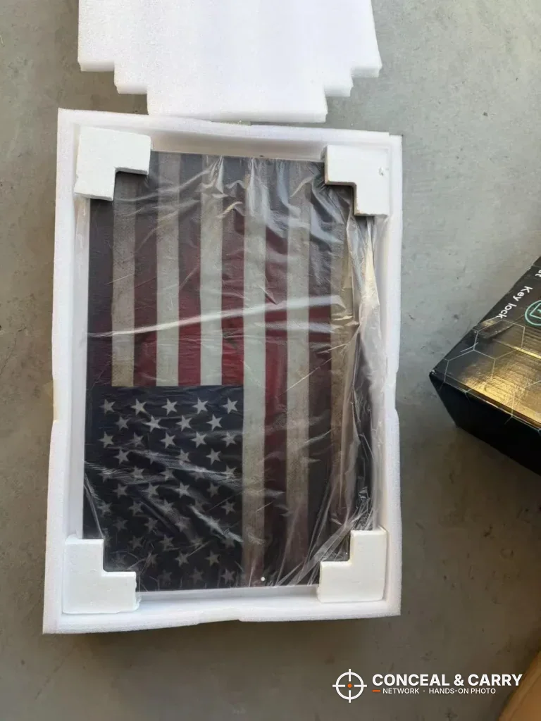 PJJSZST hidden wall gun safe in its box, flag front wrapped in plastic with foam corners