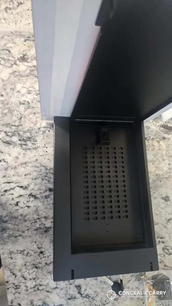 Inside the PJJSZST wall safe, a black interior with a perforated back panel