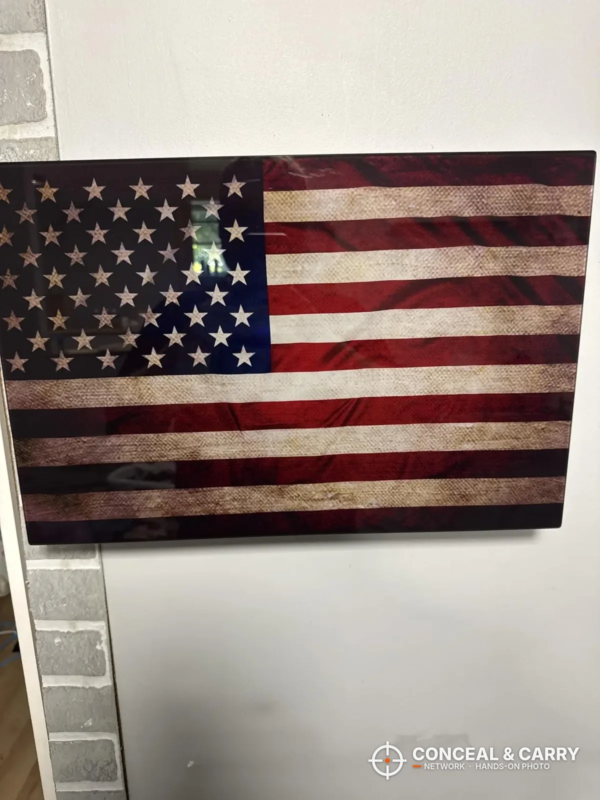 PJJSZST hidden wall gun safe hung on a white wall with the flag front facing out