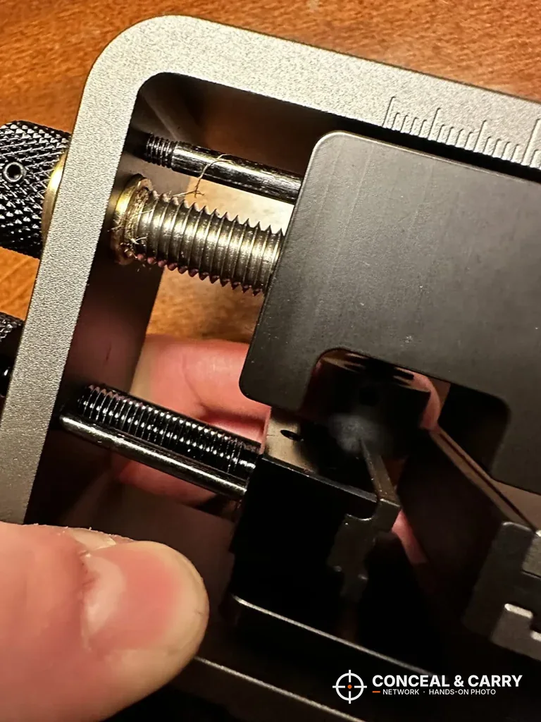 Close-up of the Pridefend sight pusher clamp and push block with a thumb on the jaw