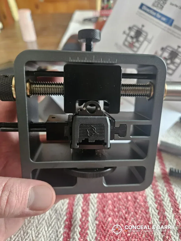 Glock slide clamped in the Pridefend sight pusher, held in hand
