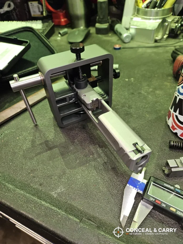 Pridefend sight pusher on a workbench mat with a slide clamped and calipers in front