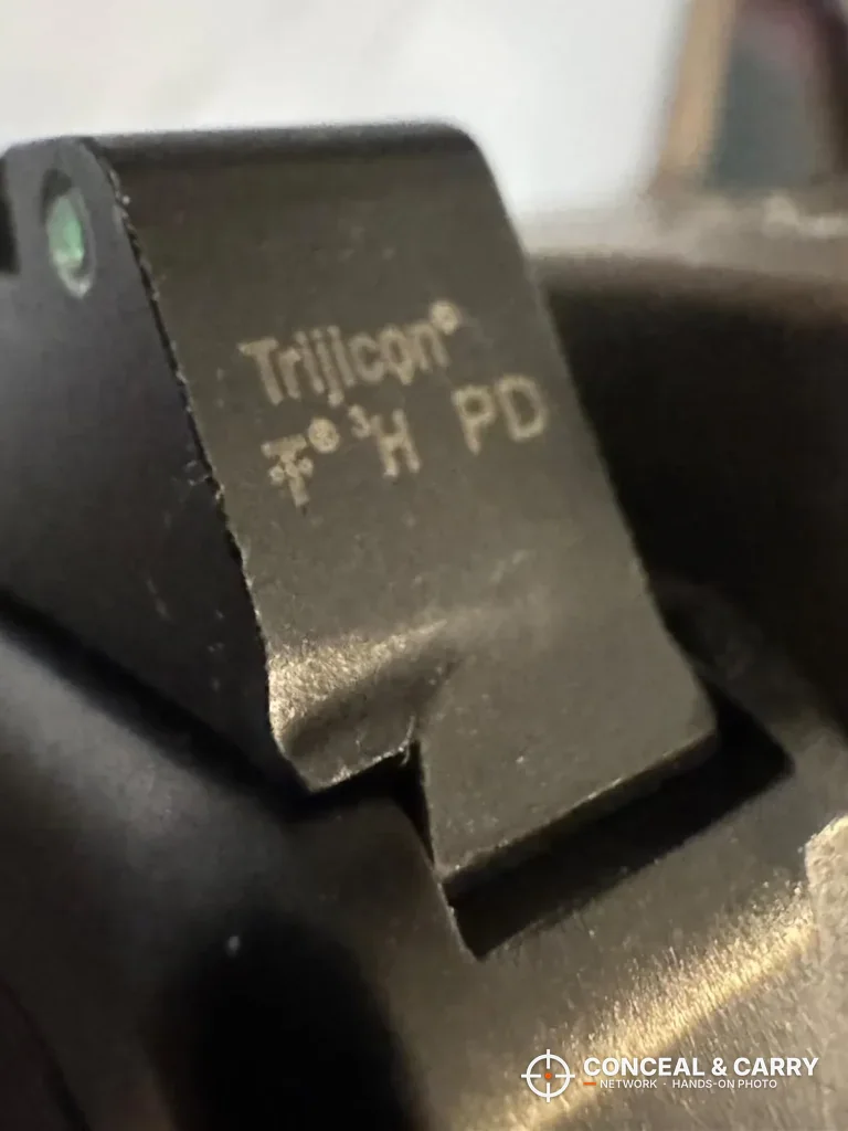 Close-up of a Trijicon-marked rear sight in a Glock slide dovetail