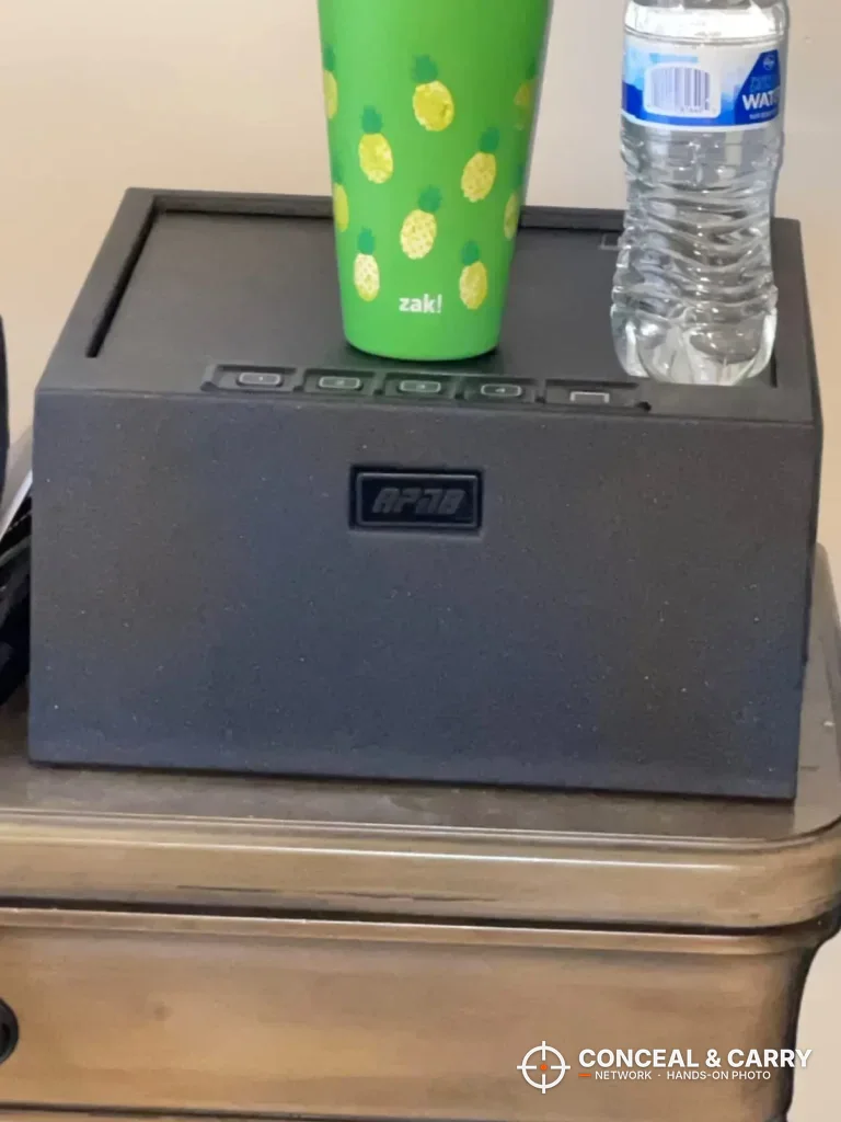 RPNB 4-pistol safe closed on a nightstand with a cup and water bottle on the lid