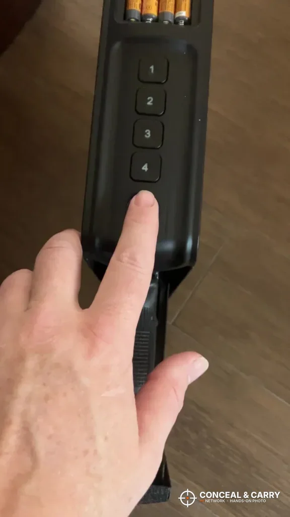 Finger on the RPNB bedside safe keypad with batteries visible at the top end