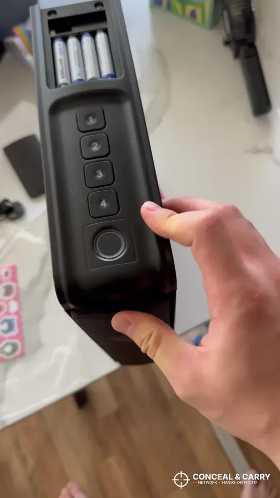 Hand holding the RPNB bedside safe showing its keypad, fingerprint reader and battery compartment
