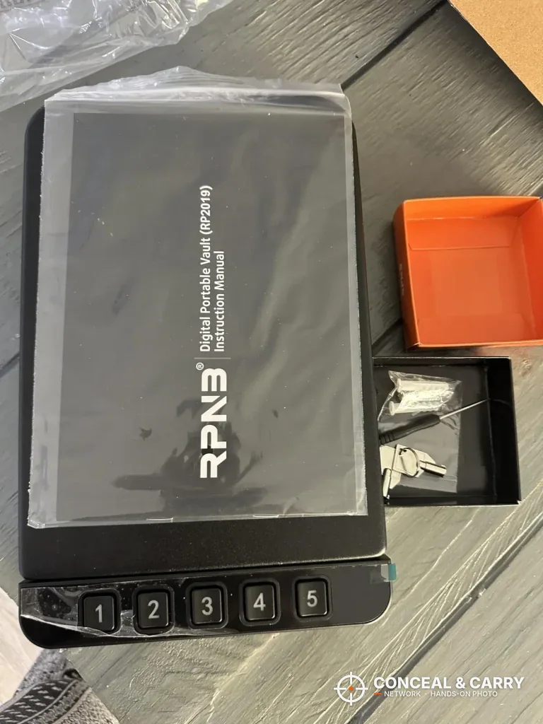 RPNB car gun safe in its plastic wrap with the manual on top and keys in a tray