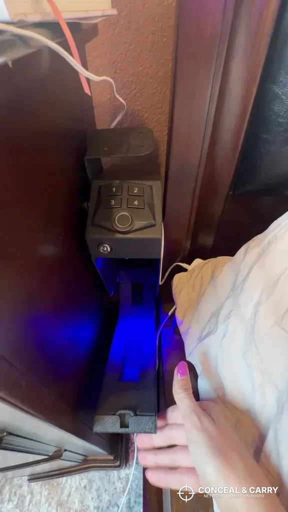 Hand reaching for the RPNB wall-mounted pistol safe mounted on wooden furniture