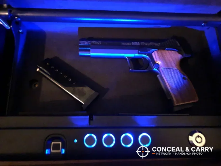 SentrySafe QAP2BLX open with the blue interior light on a pistol and magazine