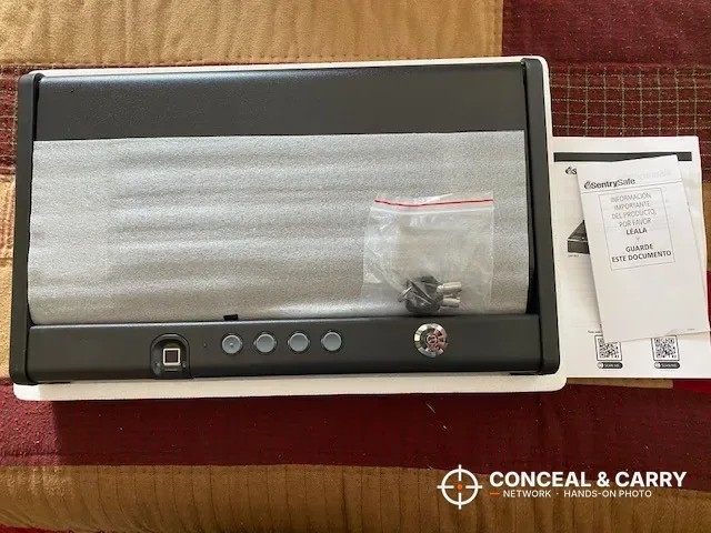 SentrySafe QAP2BLX unboxed with foam wrap, a parts bag and the manual