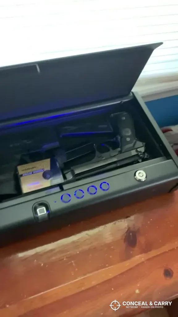 SentrySafe QAP2BLX lid up with blue light on the keypad and a pistol inside