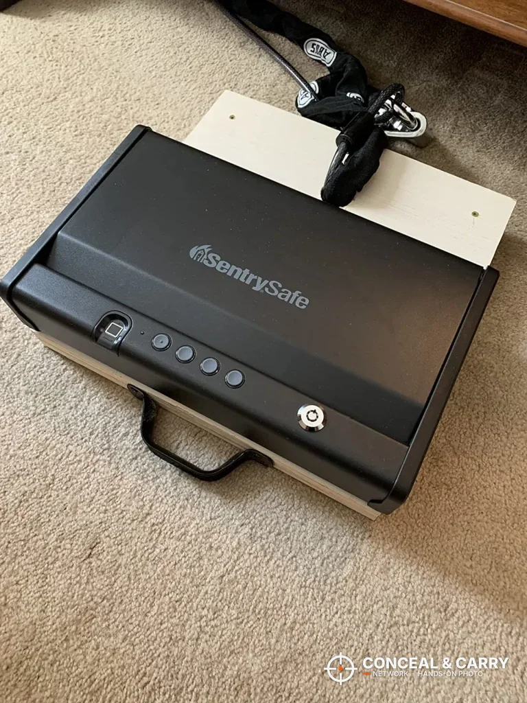 SentrySafe QAP2BLX closed on carpet beside a white board and bracket