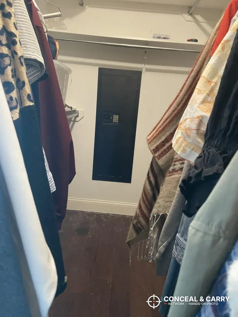 SnapSafe in-wall long gun safe in a walk-in closet wall between hanging clothes