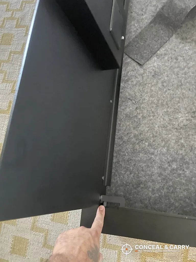 Finger pointing to the bottom corner of the open SnapSafe door