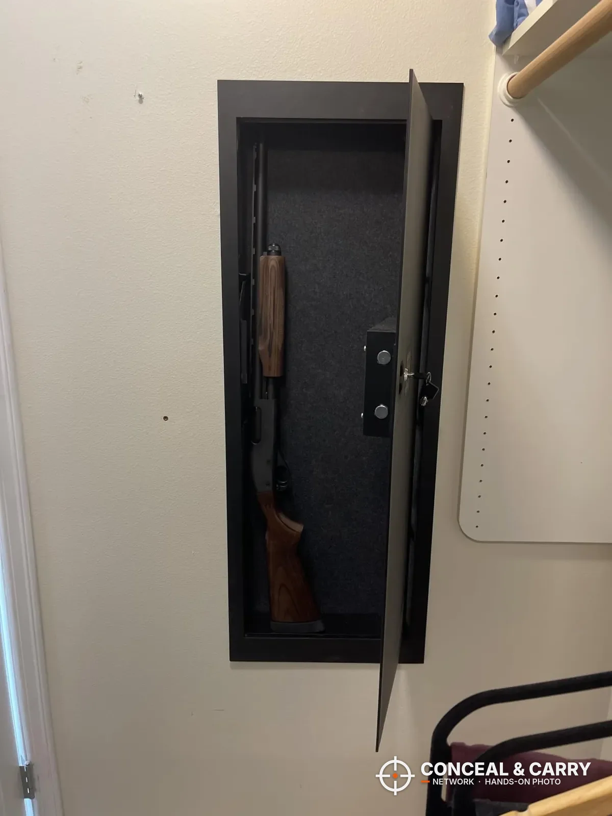 SnapSafe in-wall long gun safe set into a wall, door open with a wood-stocked long gun inside