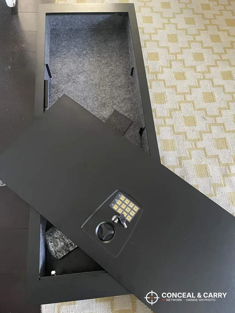 SnapSafe in-wall safe lying on the floor with the door partly open and a hardware bag inside