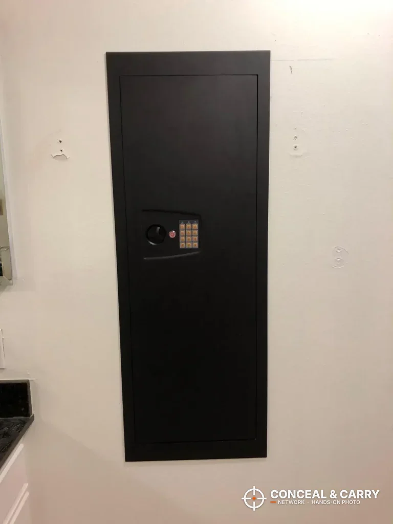 SnapSafe in-wall long gun safe installed flush in a wall, door closed with the keypad showing