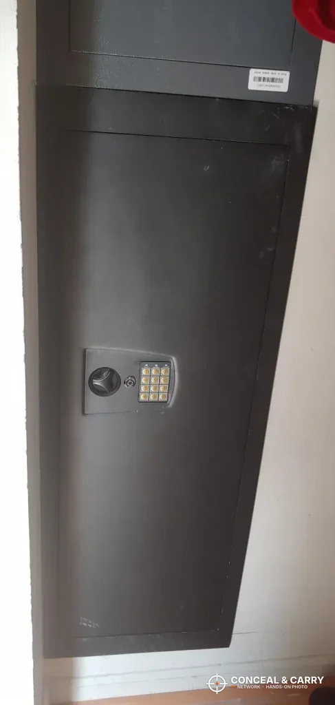 SnapSafe in-wall long gun safe standing closed, keypad on the door