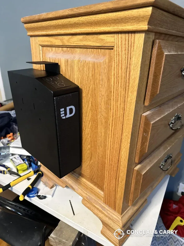 Urban Deco biometric pistol safe mounted on the side of a wooden nightstand