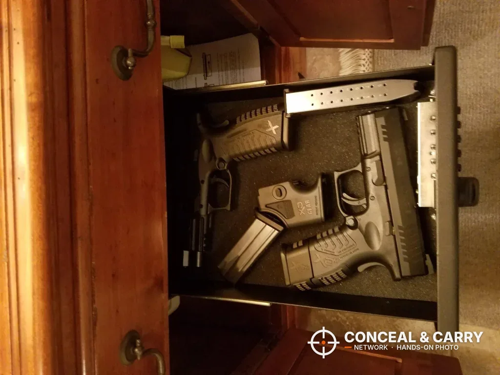 V-Line Slide-Away drawer open inside a wooden cabinet with two pistols and a magazine