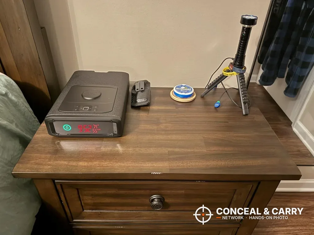 Vaultek DS2i Smart Station sitting on a wooden nightstand with its front display lit