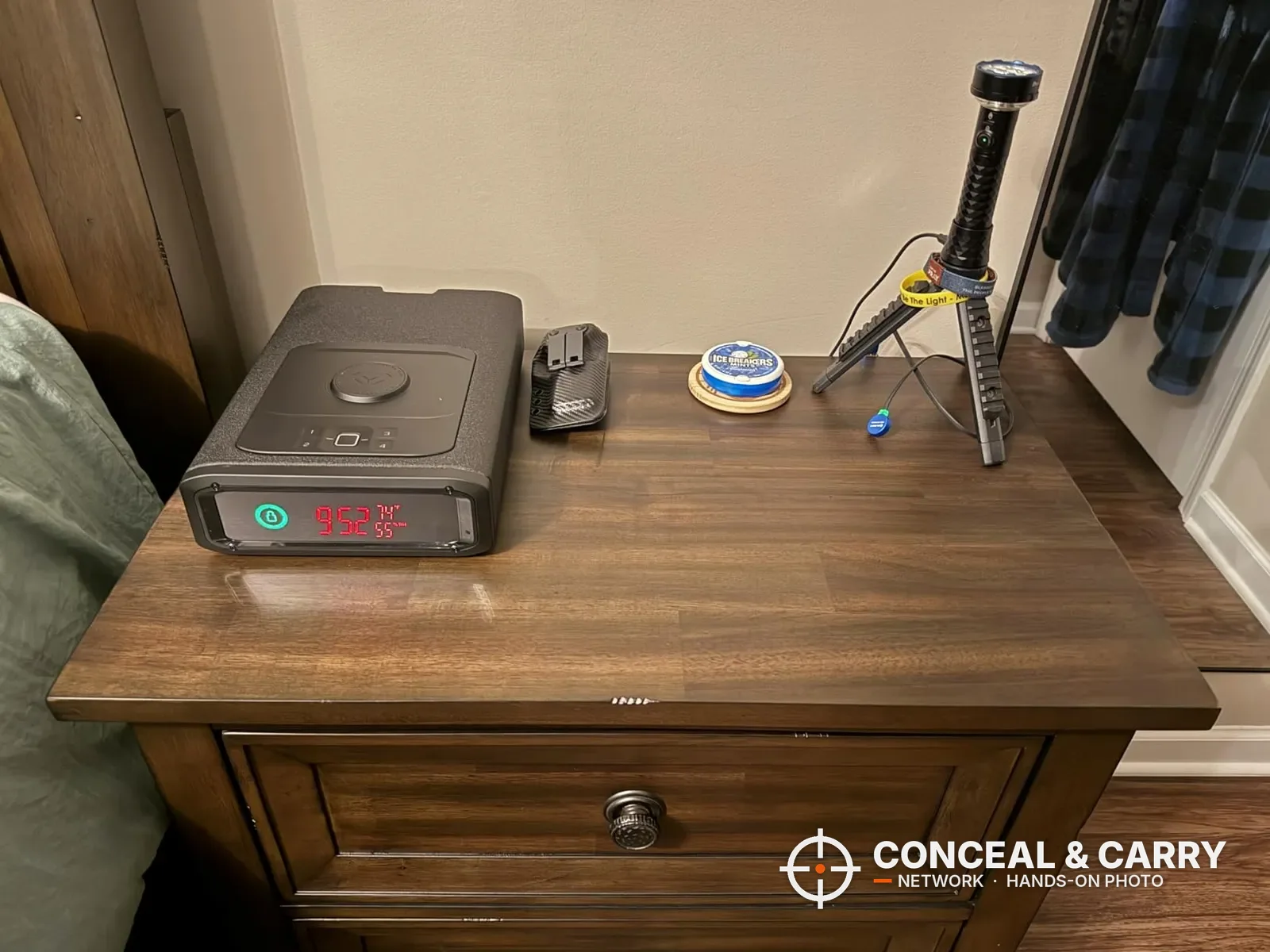 Vaultek DS2i Smart Station sitting on a wooden nightstand with its front display lit