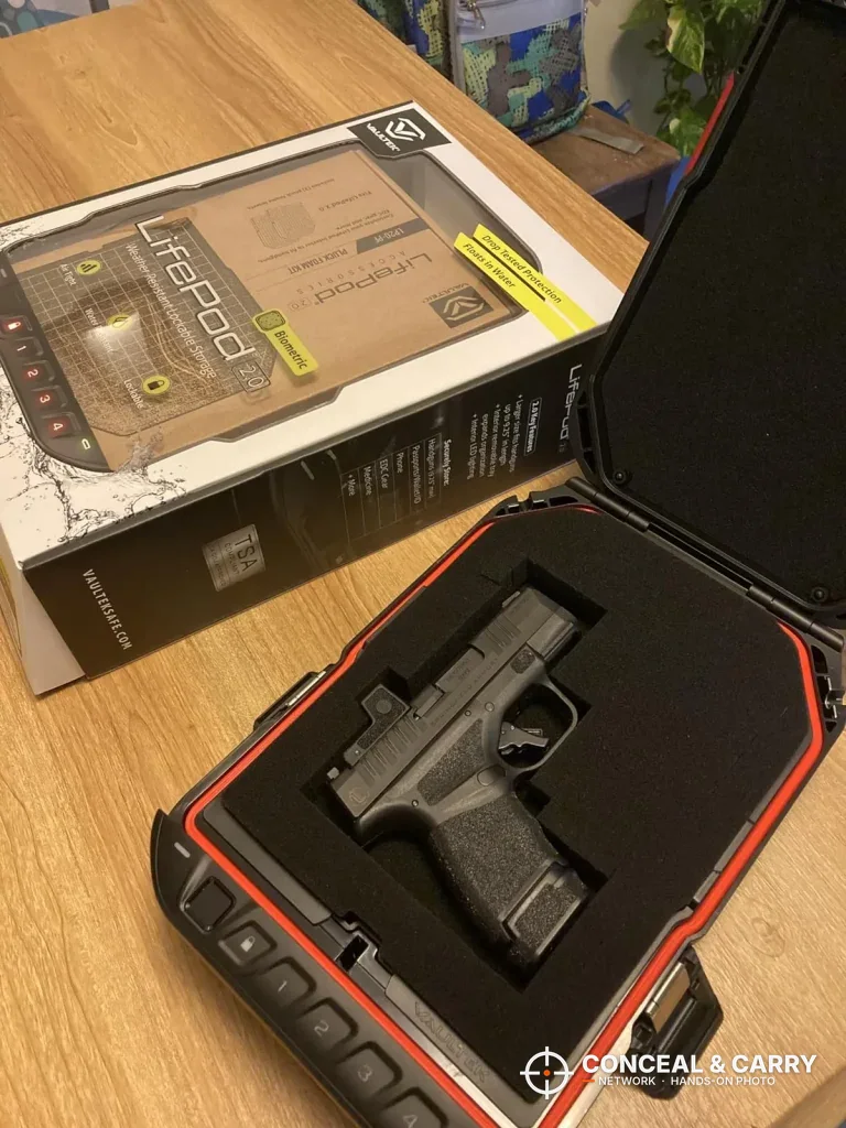 Vaultek LifePod 20 Biometric open next to its retail box with a compact pistol in the foam