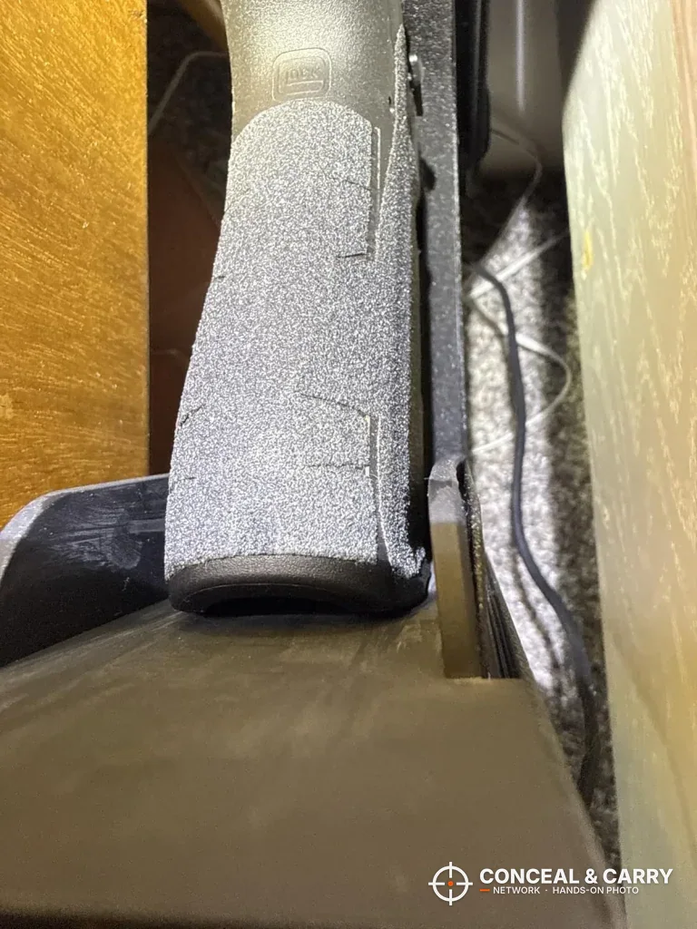Pistol grip standing up in the open Vaultek Slider Series drawer beside a wooden panel
