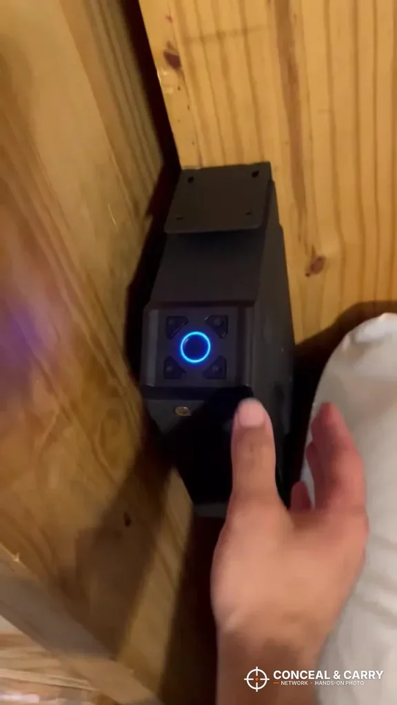 Hand reaching for the lit pad on a VERPROOF gun safe mounted at the bedside