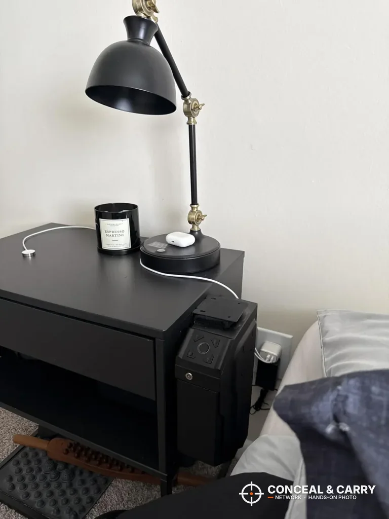 VERPROOF gun safe attached to the side of a black nightstand under a lamp