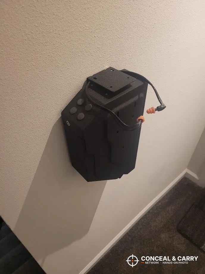 VERPROOF gun safe mounted on a bedroom wall with a cord running from it