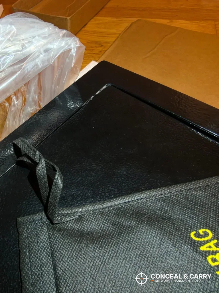 Accessory bag lying on the door of the VEVOR hidden wall gun safe