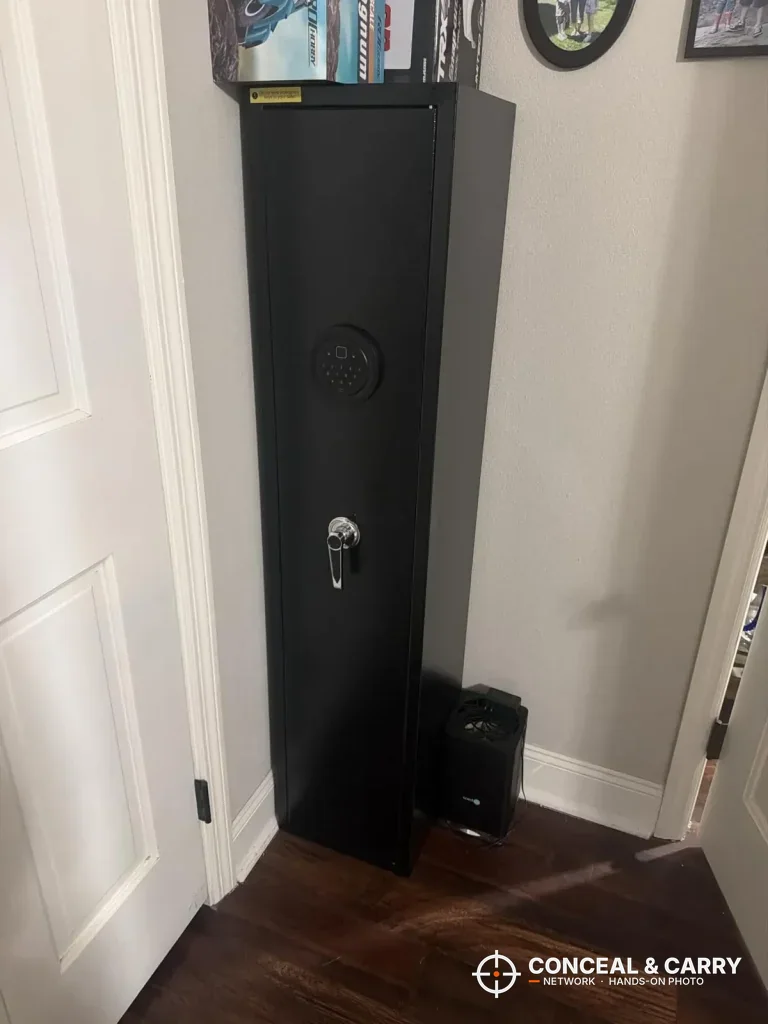 Vrothkain 3-5 gun biometric safe standing closed in a corner beside a door