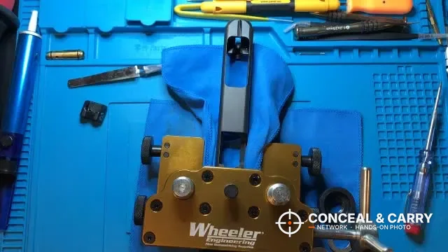 Wheeler sight tool on a blue gun mat with a bare pistol slide and small tools