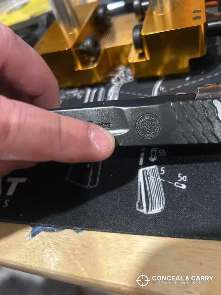 Pistol slide on a bench mat beside the Wheeler sight tool