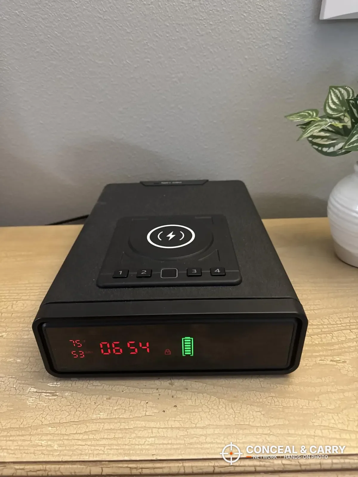 XDeer wireless charging biometric safe on a dresser with the clock display lit