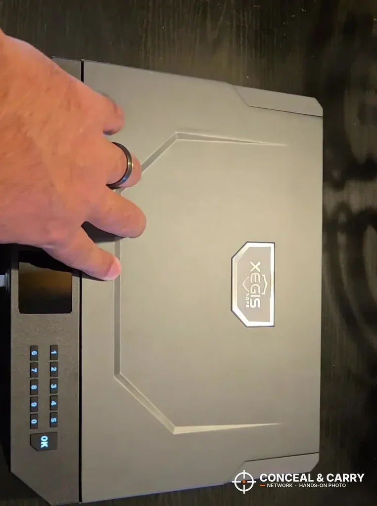 Hand resting on the lid of the XEGIS palm vein safe